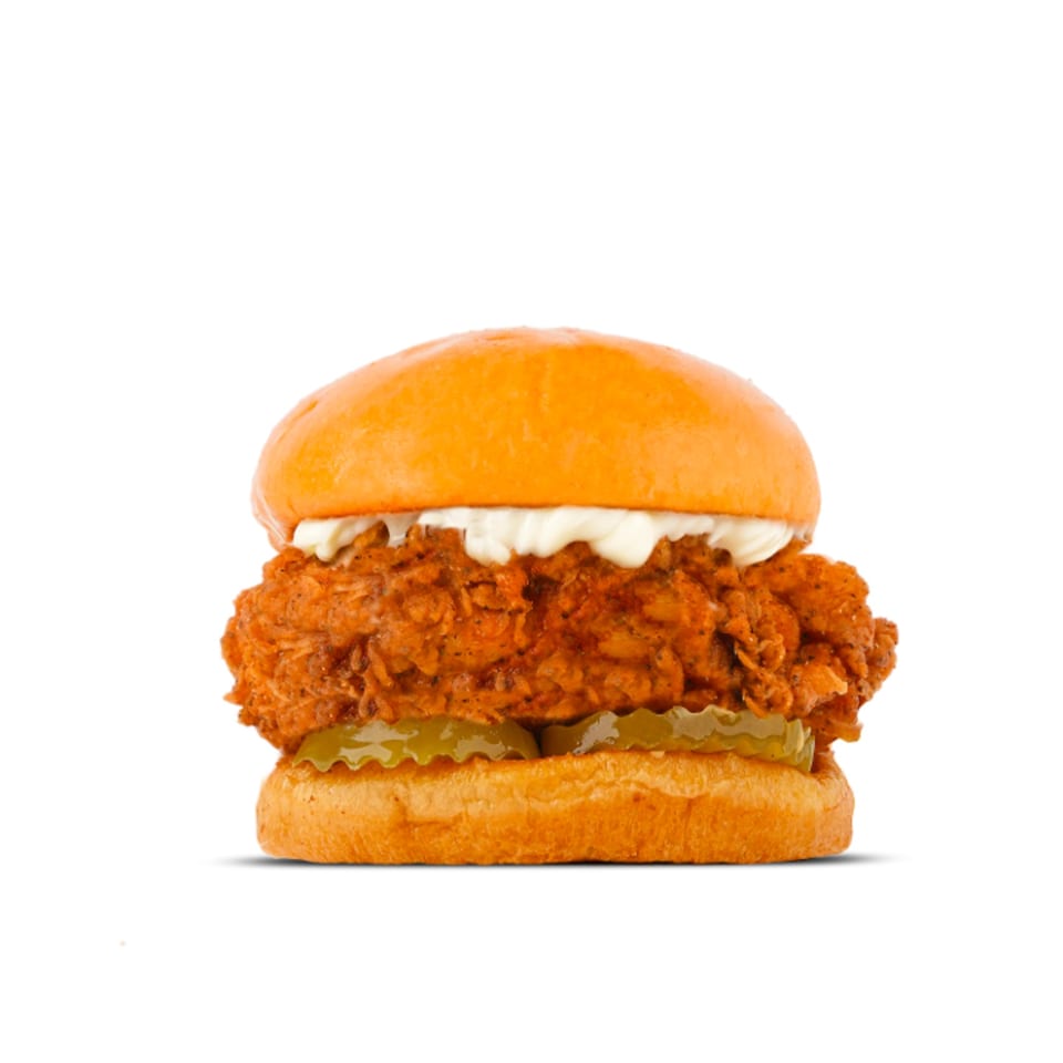 A WINGSPOT fried chicken sandwich with pickles and mayonnaise on a brioche bun.